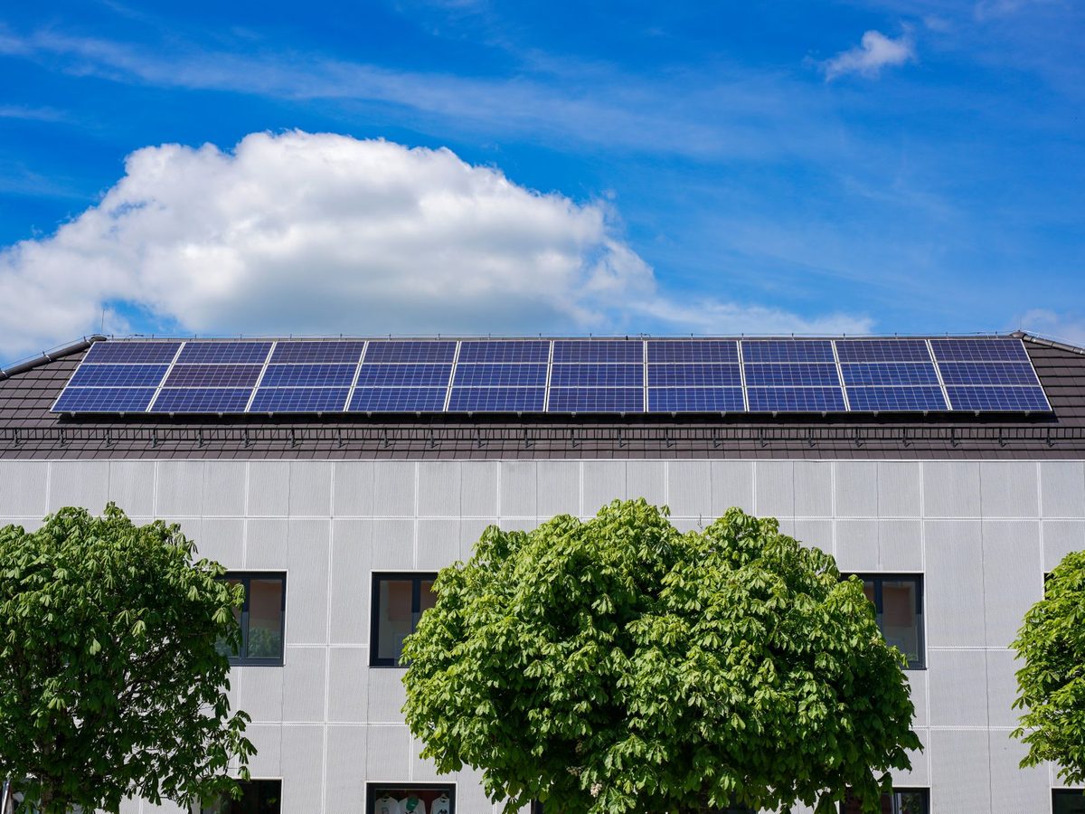 Flachdach mit langer Reihe Solarmodule über einer Fassade
