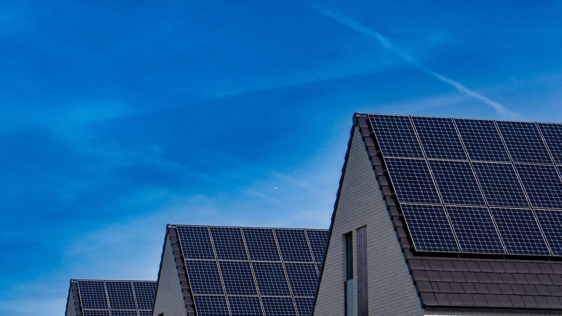 Moderne Häuser mit Solaranlagen auf dem Dach vor blauem Himmel